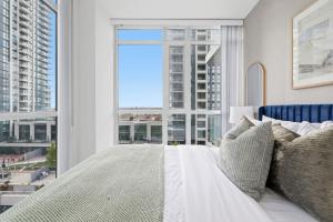 Stylish Downtown - Condo Sleeps 8 - YYZ Airport في ميسيساوغا: غرفة نوم بها سرير ونافذة كبيرة