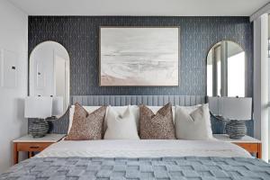 Stylish Downtown - Condo Sleeps 8 - YYZ Airport في ميسيساوغا: غرفة نوم بسرير كبير مع مرايين