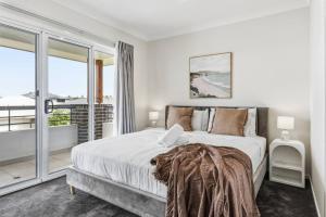 Modern Family Home in Peaceful Pallara 4BR Comfort في Algester: غرفة نوم بيضاء مع سرير كبير وشرفة