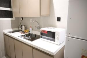 una cocina con microondas y nevera en إس بي واي للشقق المخدومة - SBY Serviced Apartments, en Buraidah