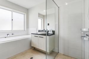 Modern Family Home in Peaceful Pallara 4BR Comfort في Algester: حمام أبيض مع حوض ومغسلة وحوض استحمام +30 صورة