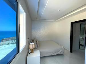 Un dormitorio con una cama y una ventana grande. en Luxurious condo with patio and terrace, en Alhucemas
