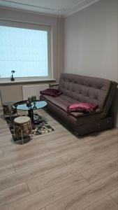 a living room with a brown couch and a table at Kambarių nuoma Kaune Taikos pr in Kaunas