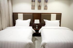 Dos camas en una habitación de hotel con sábanas blancas. en إس بي واي للشقق المخدومة - SBY Serviced Apartments, en Buraidah