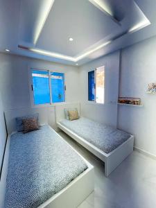 Dos camas en una habitación con dos ventanas. en Luxurious condo with patio and terrace, en Alhucemas