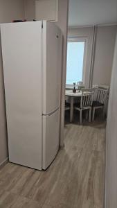 a white refrigerator in a living room with a table at Kambarių nuoma Kaune Taikos pr in Kaunas +4 photos