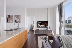 Sleek Sq 1 Downtown Condo - 4 beds - Parking في ميسيساوغا: غرفة معيشة بيضاء مع تلفزيون وأريكة