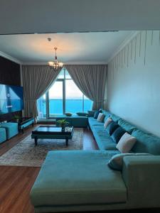 Sand And Beachfront Havens with sea view&pool&Gym&jacuzz في عجمان: غرفة معيشة مع أريكة زرقاء وتلفزيون