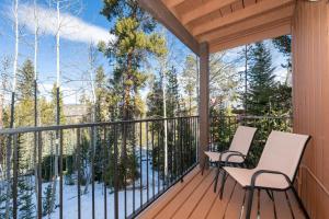 a deck with two chairs and a view of the woods at Beaver Village Unit #0724 in Winter Park