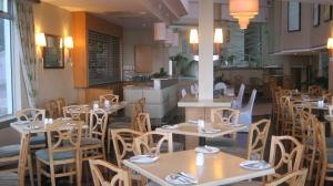 a restaurant with wooden tables and chairs and a kitchen at La Mercy Beach Hotel in La Mercy