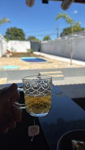 a hand holding a glass of liquid on a table at Chácara Tubaras in Uberlândia