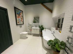 a bathroom with a tub and a toilet and a sink at Entertainment Packed 3BDR Barn at Stevenage in Shephall