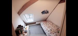a small attic room with a bed and a window at Entertainment Packed 3BDR Barn at Stevenage in Shephall