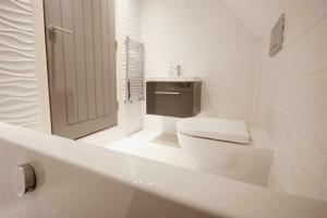 a white bathroom with a toilet and a sink at Entertainment Packed 3BDR Barn at Stevenage in Shephall +12 photos