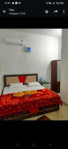 a bedroom with a bed with a red blanket at Manglam House in Ayodhya