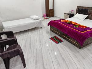 a bedroom with two beds and a purple blanket on the floor at Manglam House in Ayodhya