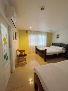 a room with two beds and a table in it at Moradok Thai Guesthouse in Phra Nakhon Si Ayutthaya