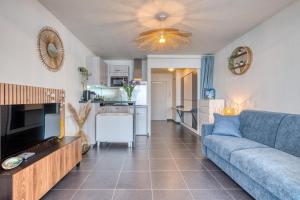 een woonkamer met een blauwe bank en een keuken bij Premium Ocean View Studio, Balcony & Pool in Les Sables-dʼOlonne