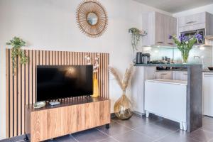 een woonkamer met een flatscreen-tv op een houten entertainmentcentrum bij Premium Ocean View Studio, Balcony & Pool in Les Sables-dʼOlonne +5 foto's