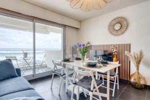 een eetkamer met een tafel en uitzicht op de oceaan bij Premium Ocean View Studio, Balcony & Pool in Les Sables-dʼOlonne