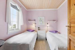 2 Betten in einem Zimmer mit lila Wänden und einem Fenster in der Unterkunft 3690 Nexø - Hovedgade 2 in Snogebæk
