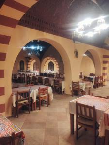 ein Restaurant mit Tischen und Stühlen in einem Raum in der Unterkunft Siwa Safari Paradise Hotel in Siwa