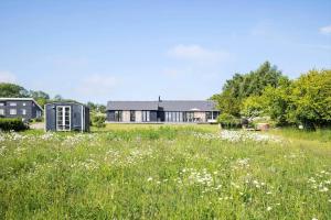 a house in a field with flowers in the foreground at 6798-Allinge-Aeblebakken-9 in Allinge