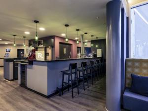 a kitchen with a bar with stools and a couch at Mercure Stuttgart Zuffenhausen in Stuttgart