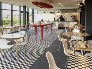 ein Restaurant mit Tischen und Stühlen in einem Raum in der Unterkunft ibis Styles Le Mans Sud Mulsanne in Mulsanne