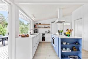 una cocina con armarios blancos y una isla azul en 3670-Nexo-Odden-11, en Bedegård
