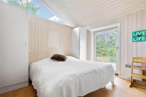 Un gato sentado en una cama en una habitación con ventana. en 3670-Nexo-Odden-11, en Bedegård