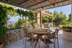 Un patio con una mesa y sillas de madera y un muro de piedra. en Villa Levantina, en Porto Heli