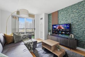 Tropical Designer King Suite - Sleeps 5 - Parking في ميسيساوغا: غرفة معيشة مع أريكة وتلفزيون بشاشة مسطحة