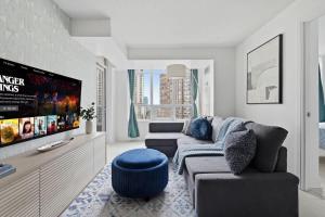 Designer 2BR - King Suite - Rare 2 Parking - YYZ في ميسيساوغا: غرفة معيشة مع أريكة وتلفزيون