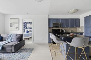 Designer 2BR - King Suite - Rare 2 Parking - YYZ في ميسيساوغا: مطبخ وغرفة معيشة مع أريكة وطاولة