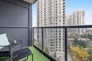 Designer 2BR - King Suite - Rare 2 Parking - YYZ في ميسيساوغا: شرفة مع أريكة ونوافذ كبيرة