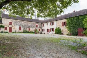 un vecchio edificio in pietra con porte rosse e un cortile di Lorette a Le Veurdre Altre 17 foto