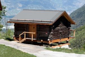 a log cabin on a hill with mountains in the background at Studio Raccard Cendré in Grône