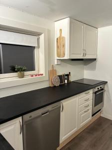 a kitchen with white cabinets and a black counter top at Leilighet i hus in Sarpsborg