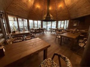 Un restaurante con mesas y sillas de madera y ventanas. en Viktan Hotel, en Bukovel