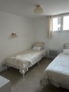 two beds in a room with white walls and windows at Charmant appartement au centre ville de Cavaillon in Cavaillon