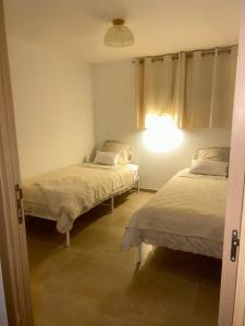a bedroom with two beds and a light on the wall at Charmant appartement au centre ville de Cavaillon in Cavaillon