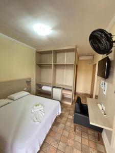 a bedroom with a white bed and a black chair at Hotel Inter Alexandria in Cândido Mota