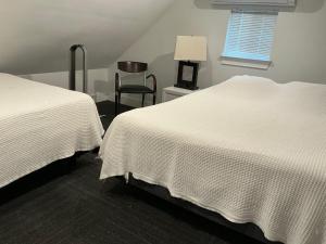 two beds in a room with a chair and a window at Cabin in the Woods in San Marcos