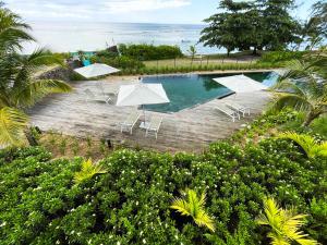 a swimming pool with umbrellas and chairs and the ocean at Ocean Point Beachfront 3-Bedroom Suites by LOV Mauritius in Pointe aux Piments