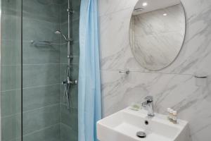 Un baño con lavabo y ducha con espejo. en Ilios and Irene 4, en Mastichari