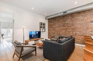 Una sala de estar con un sofá y una pared de ladrillos. en The Saddlery - Encore - 1 Block to Broadway, en Nashville