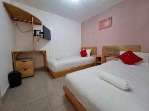 ein Hotelzimmer mit zwei Betten und einem Fernseher in der Unterkunft Hotel Dulce Luna in San Cristóbal de las Casas
