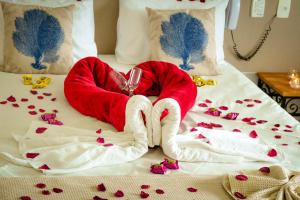 a bed with a couple of hearts and a glass of wine at VELINN Hotel Guarda Mor in São Sebastião