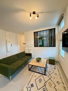 Le Jupiter, Centre ville, Parking Privé في بورجوا: غرفة معيشة مع أريكة خضراء وطاولة +صورة واحدة